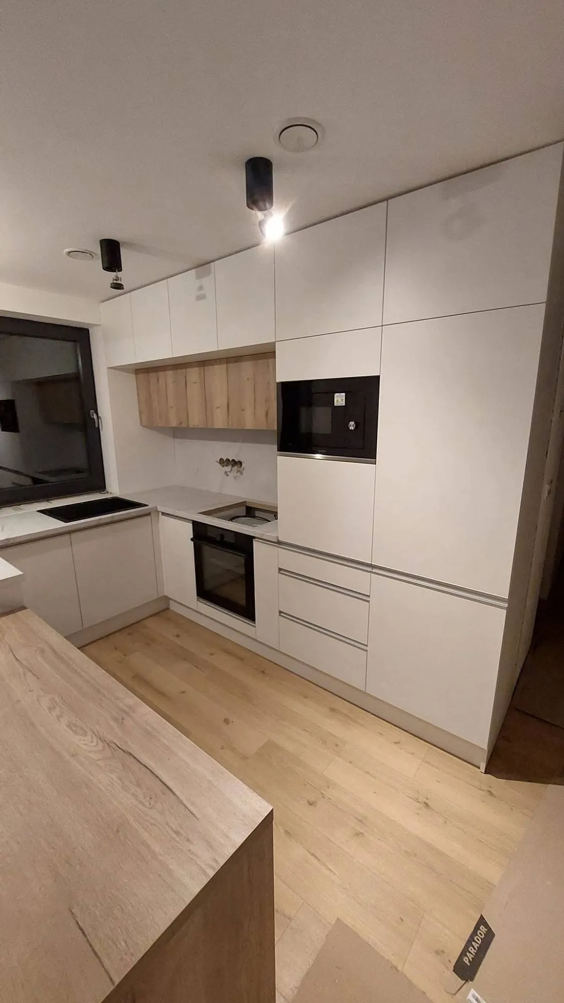 Biela kuchyňa s polostrovom a stolom – fotka 3